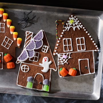 Colorful Halloween-themed gingerbread houses decorated with candy and spooky elements on a serving tray.